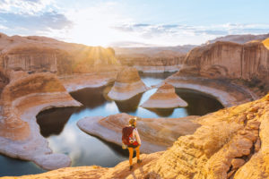 Backpacker at sunrise, Reflection Canyon, Lake Powell, Utah, US Backpacker at sunrise, Reflection Canyon, Lake Powell, Utah, US